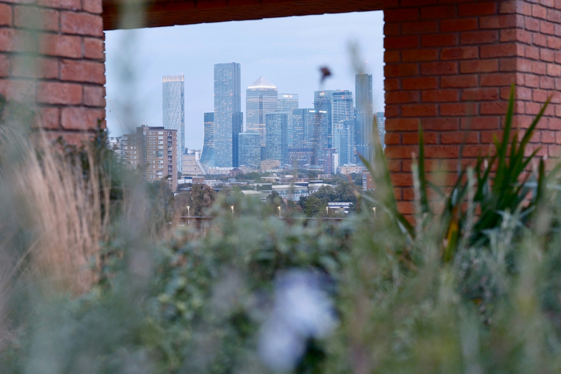 The Canary Wharf financial district viewed through a gap in a brick wall