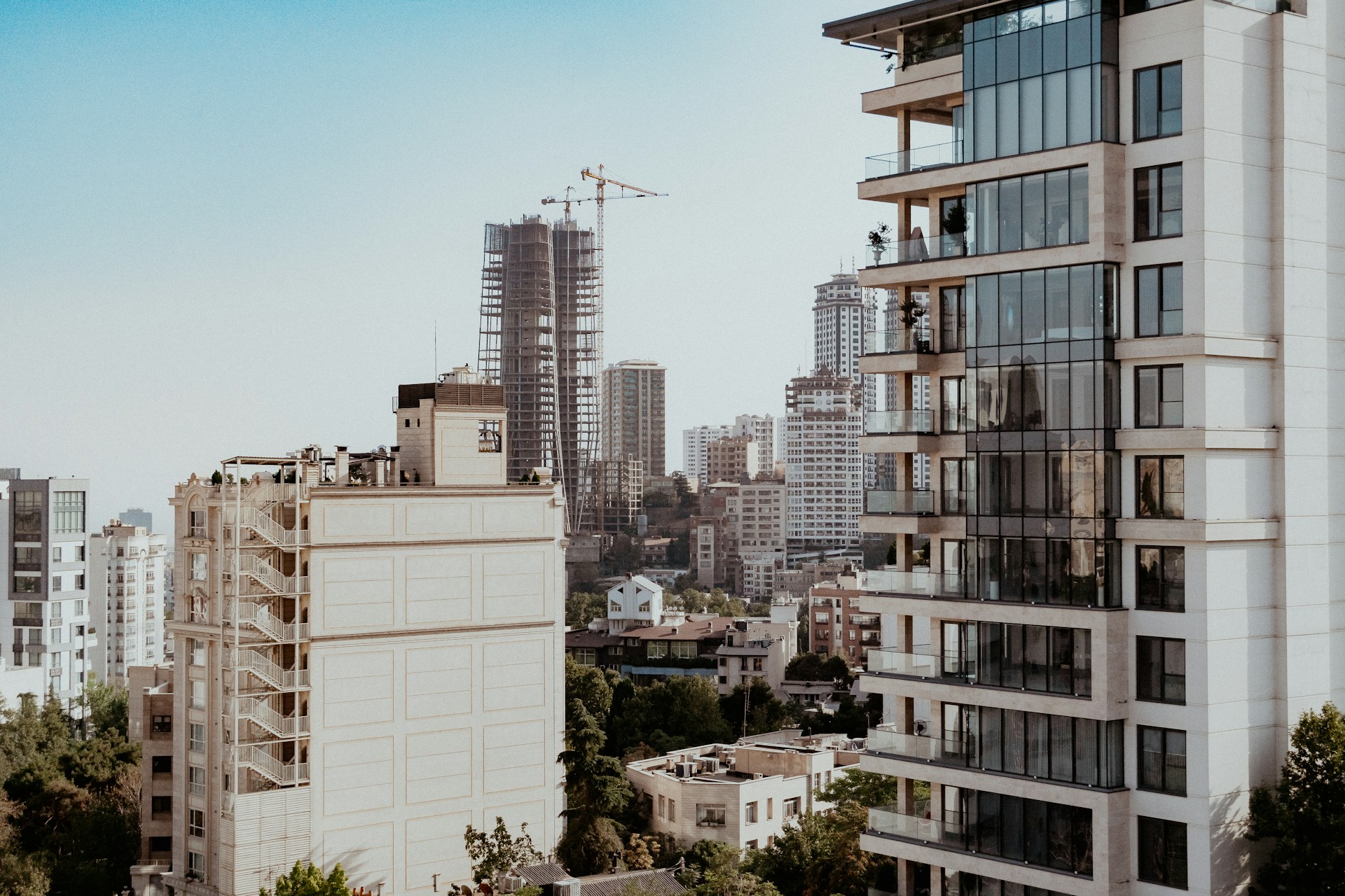 A modern city skyline with tall buildings and construction cranes