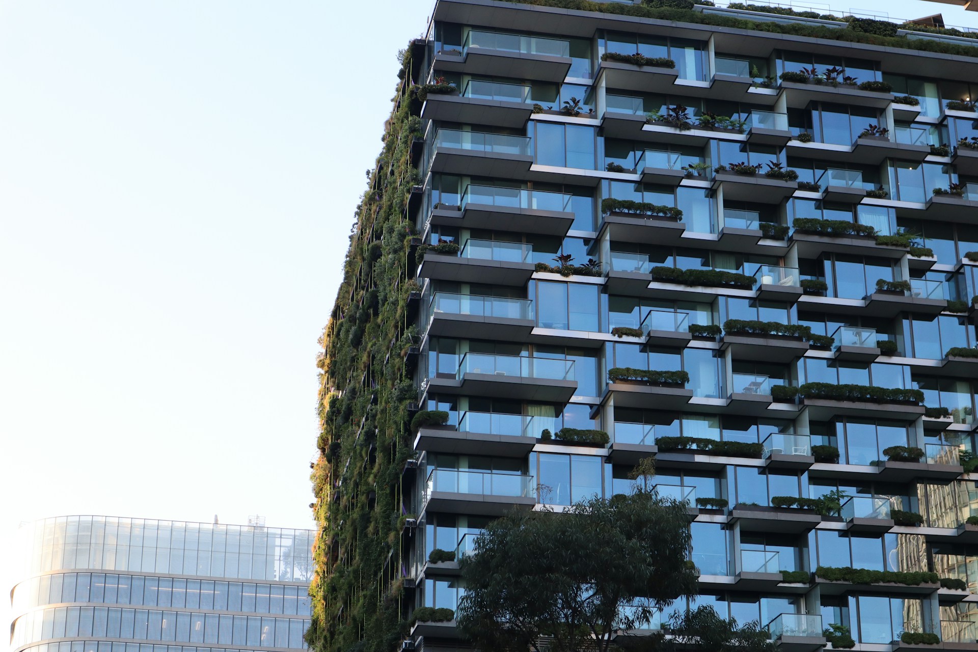 Modern residential building with planted balconies and a vertical garden covering one facade