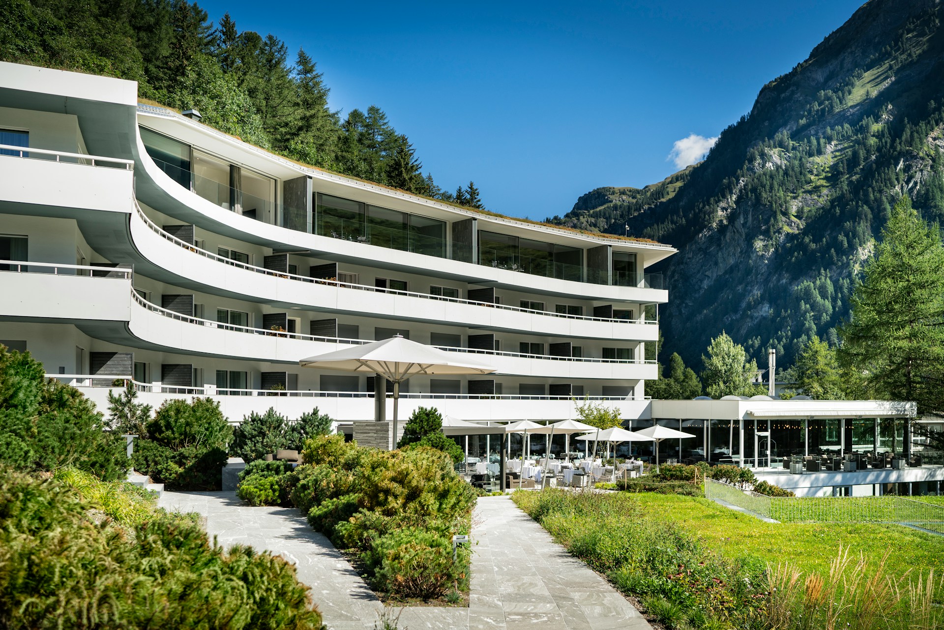 Modern hotel with curved balconies set against a mountain slope