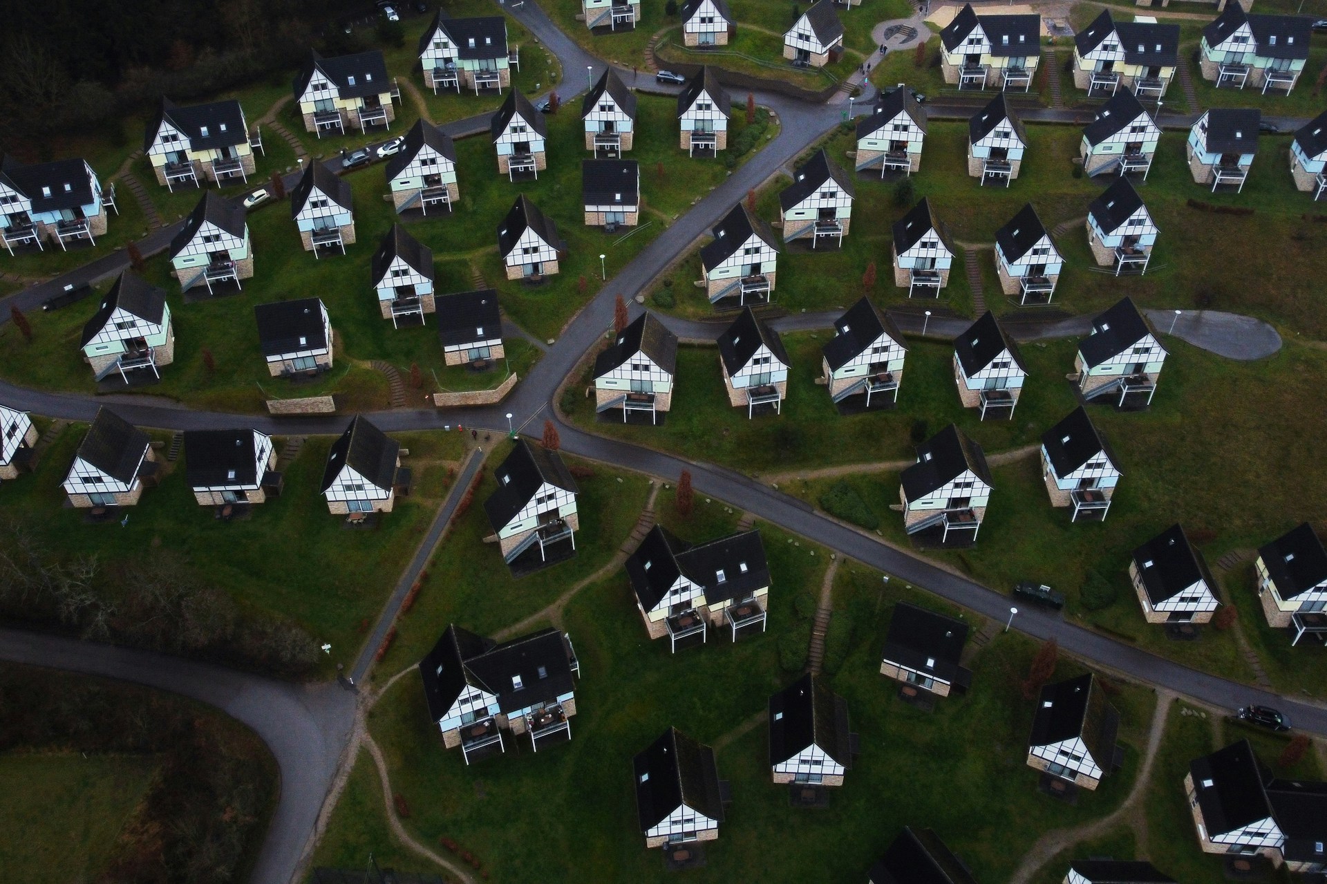 Aerial view of a residential development with rows of identical houses connected by winding roads