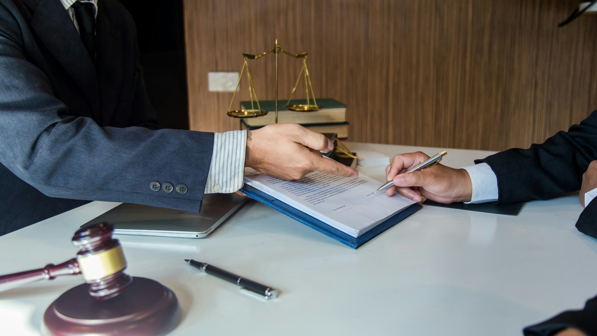Close-up of hands signing legal documents on a desk