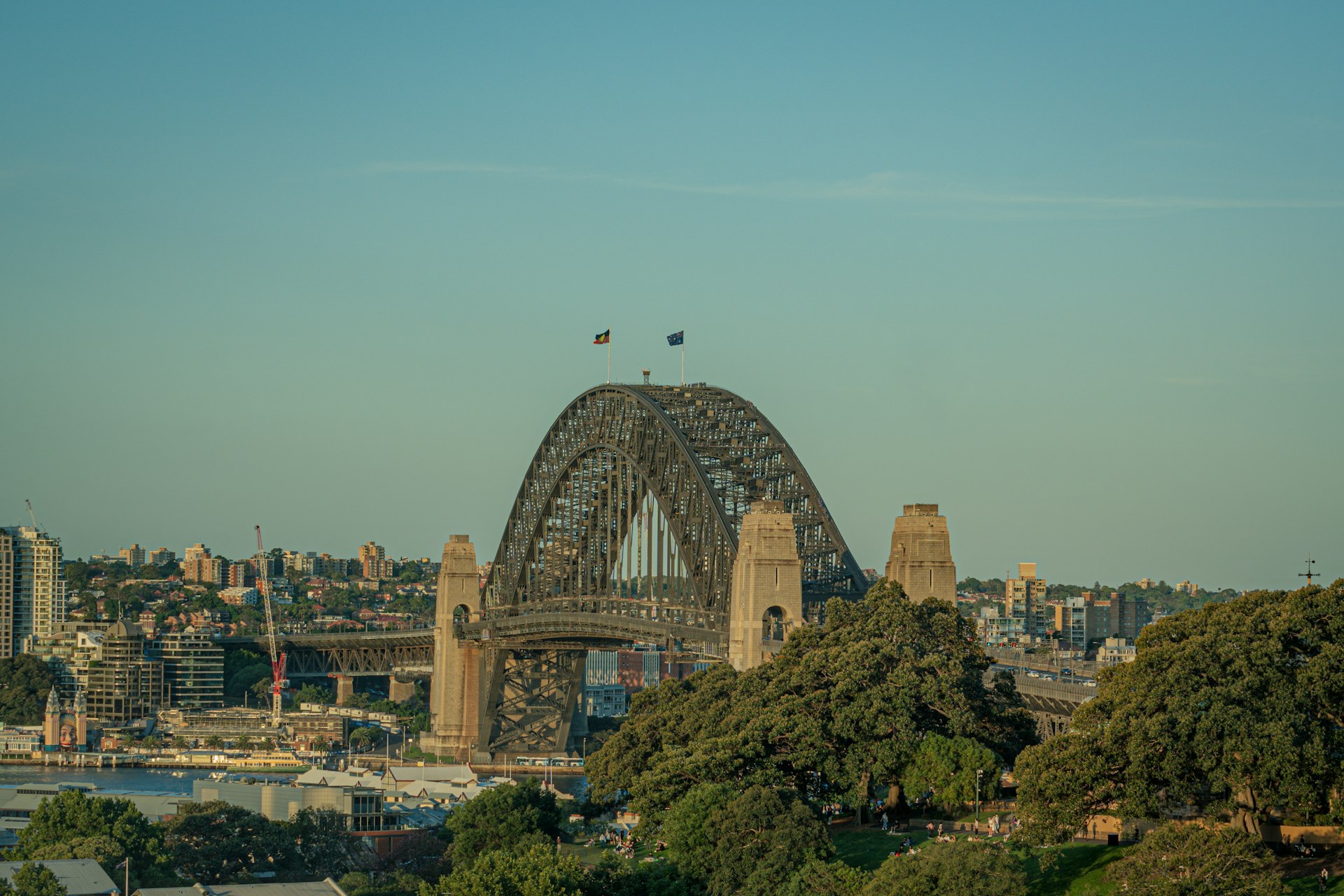 Sydney Harbour Bridge in evening light, with the harbour and residential districts behind it