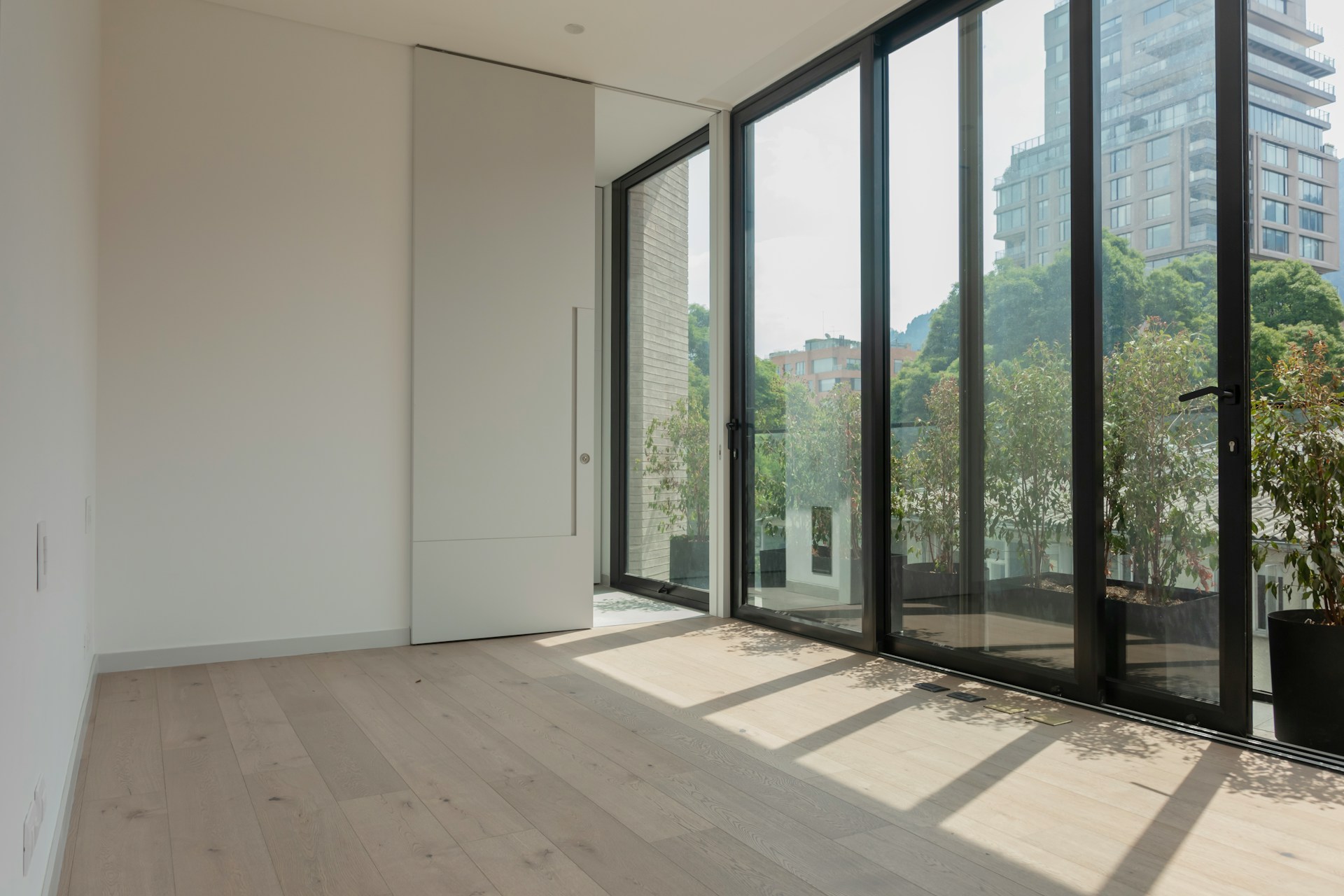Empty newly completed rental apartment with floor-to-ceiling windows and a planted terrace, ready for lease-up