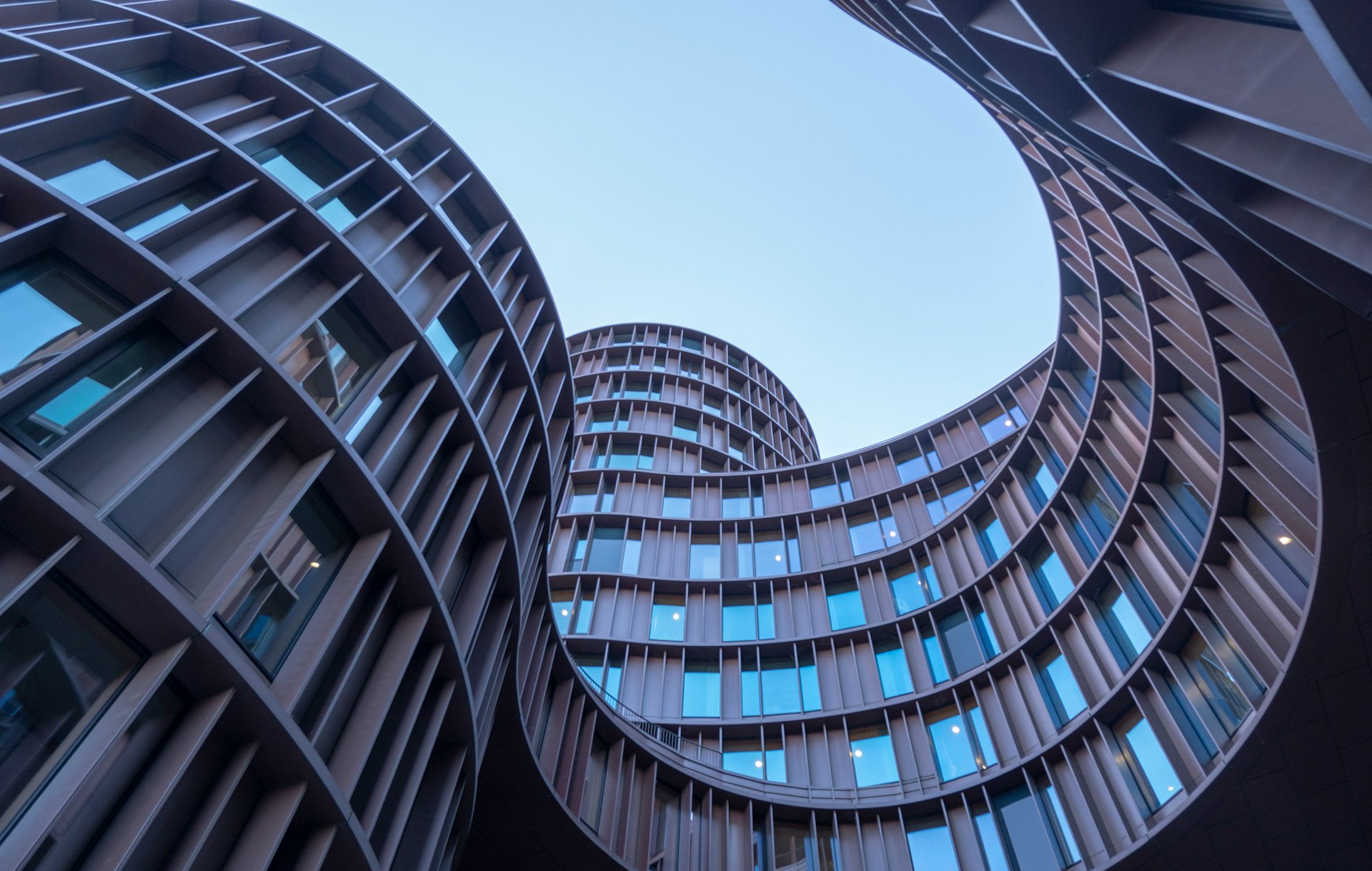 Curved cylindrical office towers seen from below against a clear sky
