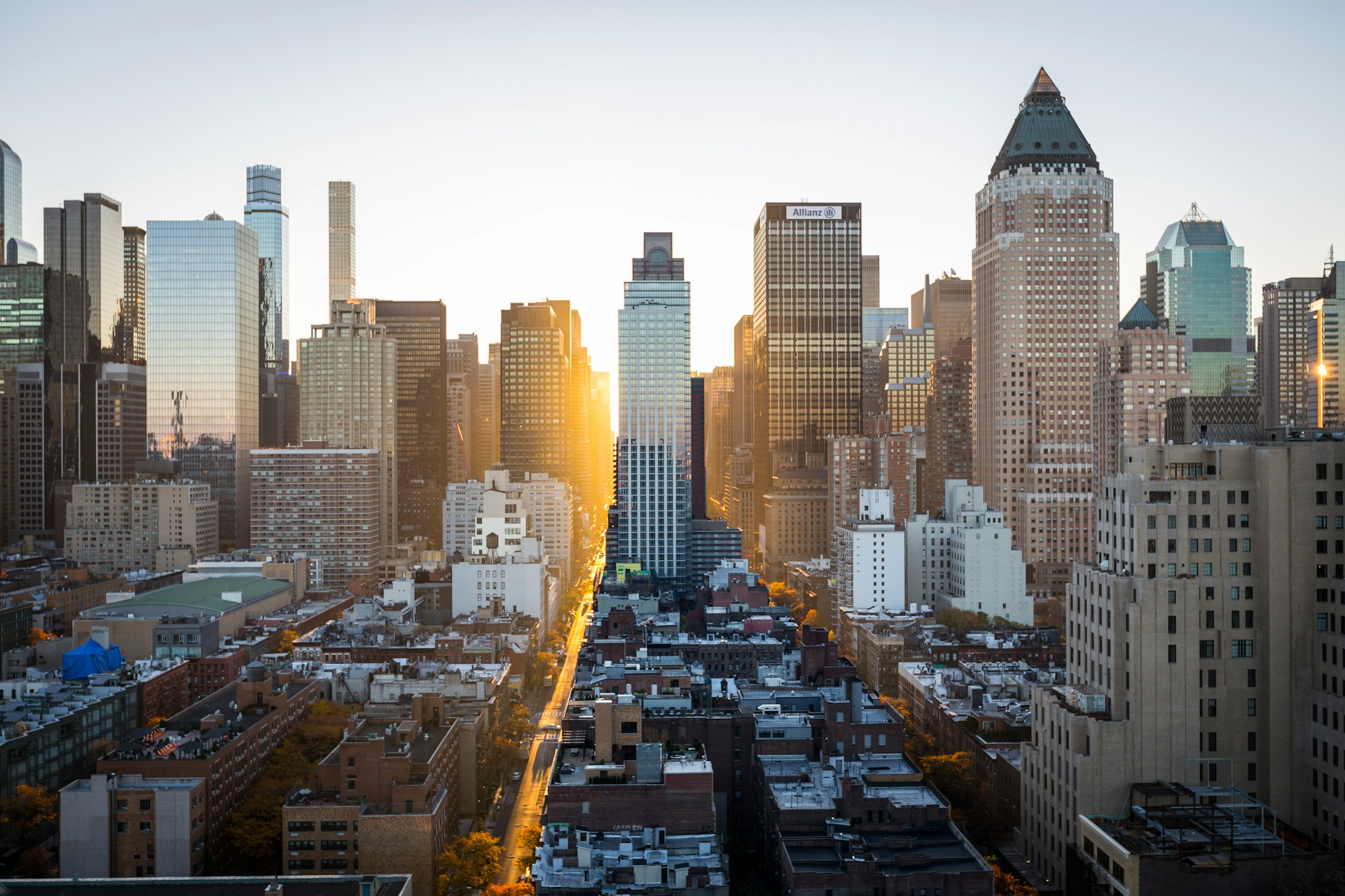 Manhattan skyline at sunset, with sunlight streaming down a street between office towers